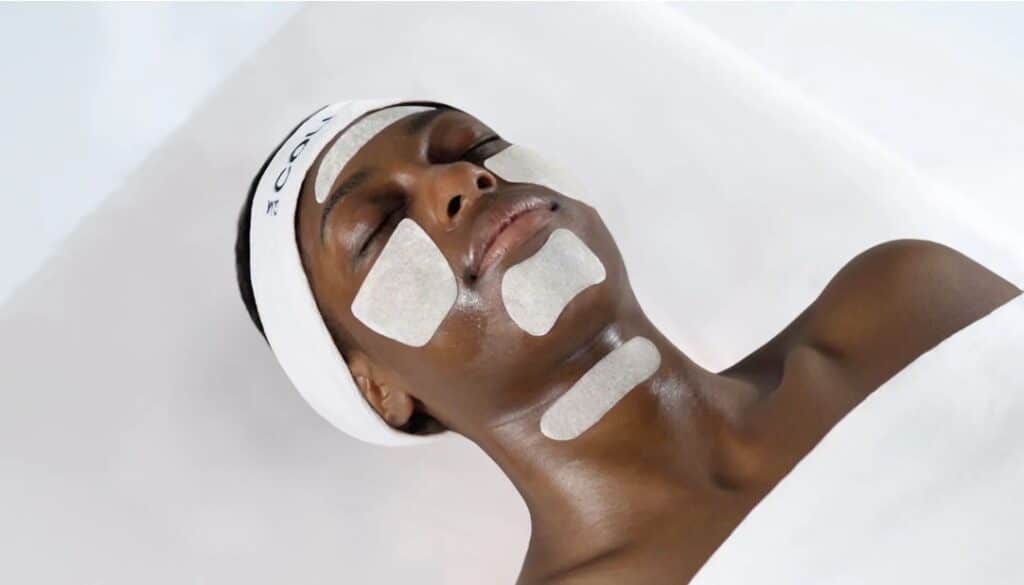 GM Collin professional facial treatment with white enzyme mask patches applied to cheeks, forehead, and neck for a targeted skin rejuvenation facial